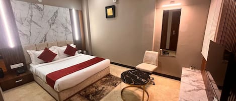 Une chambre d’hôtel moderne avec un grand lit, une petite table ronde, une chaise et un ventilateur de plafond.