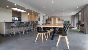 Eine moderne Küche mit Essbereich, ausgestattet mit einem großen Holztisch und schwarzen Stühlen.
