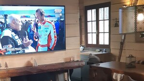 Un salon chaleureux avec une cheminée, des fauteuils confortables et un téléviseur diffusant un événement sportif.