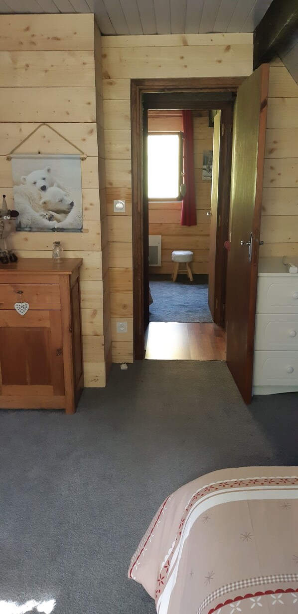 A wooden cabin room with a bed, dresser, and a painting of polar bears. - Barn for Rent in Espiaube (Saint-Lary-Soulan)
