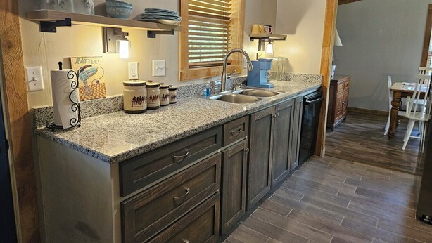 A kitchen with granite countertops, wooden cabinets, a built-in sink, and a window with blinds. - Relax in the wilderness at Bowie Acres (Bowie)