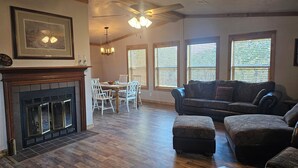 A spacious living room with a fireplace, dining area, and large windows. - Relax in the wilderness at Bowie Acres (Bowie)