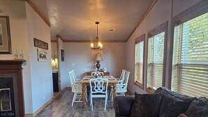 A dining area with a wooden table and chairs, a chandelier, and a fireplace. - Relax in the wilderness at Bowie Acres (Bowie)