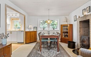 A cozy kitchen with a dining table, chairs, a fireplace, and a window with a view of greenery. - Nice home in Gistrup with WiFi (Gistrup)