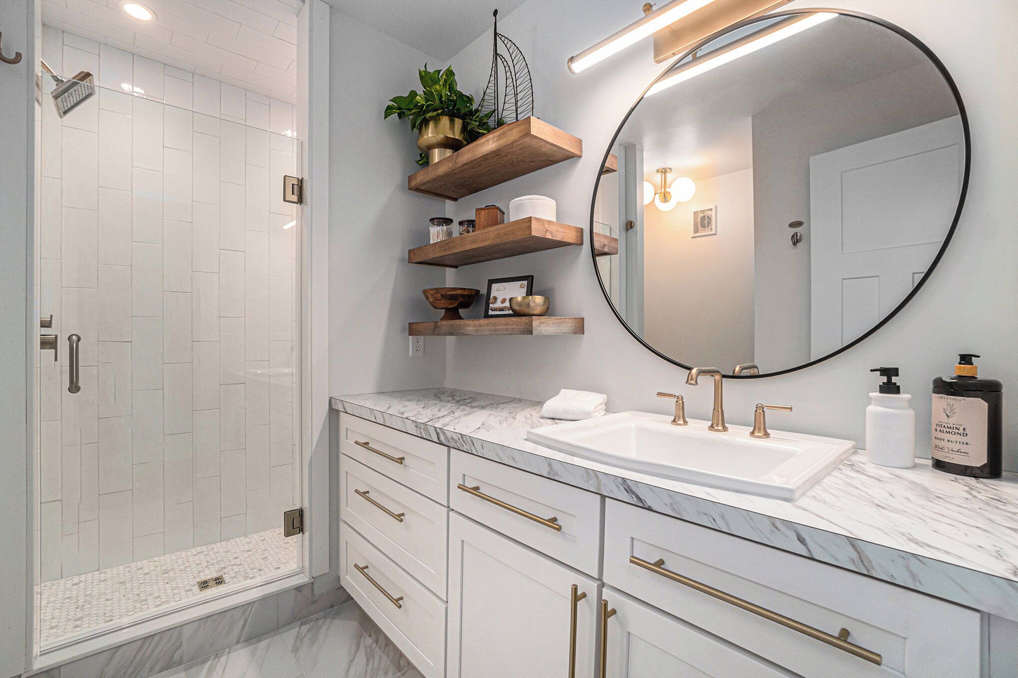 A modern bathroom with a shower, a large mirror, and marble countertops.