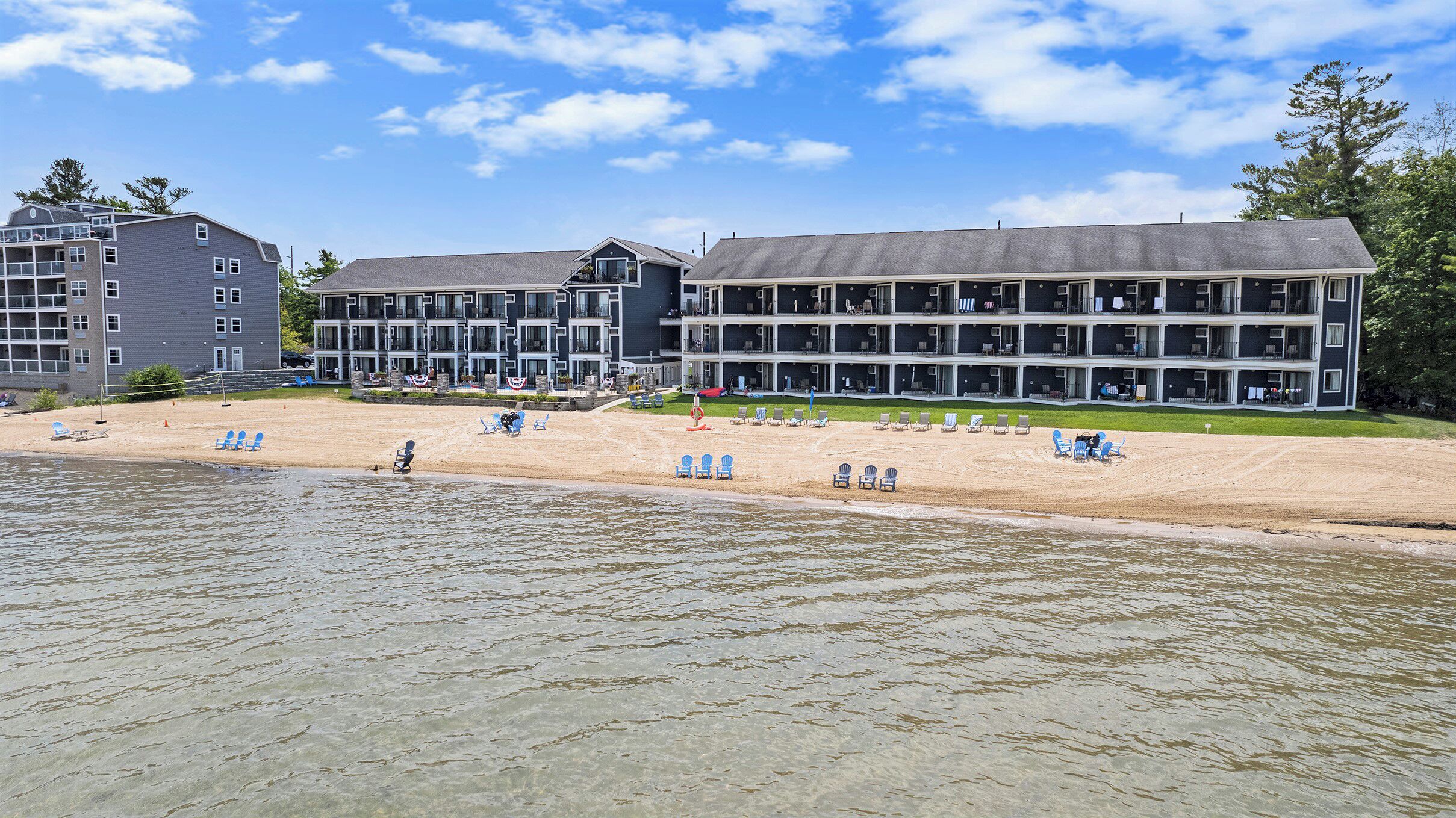 Ett hotell vid stranden med flera balkonger, en sandstrand och ett antal solstolar.