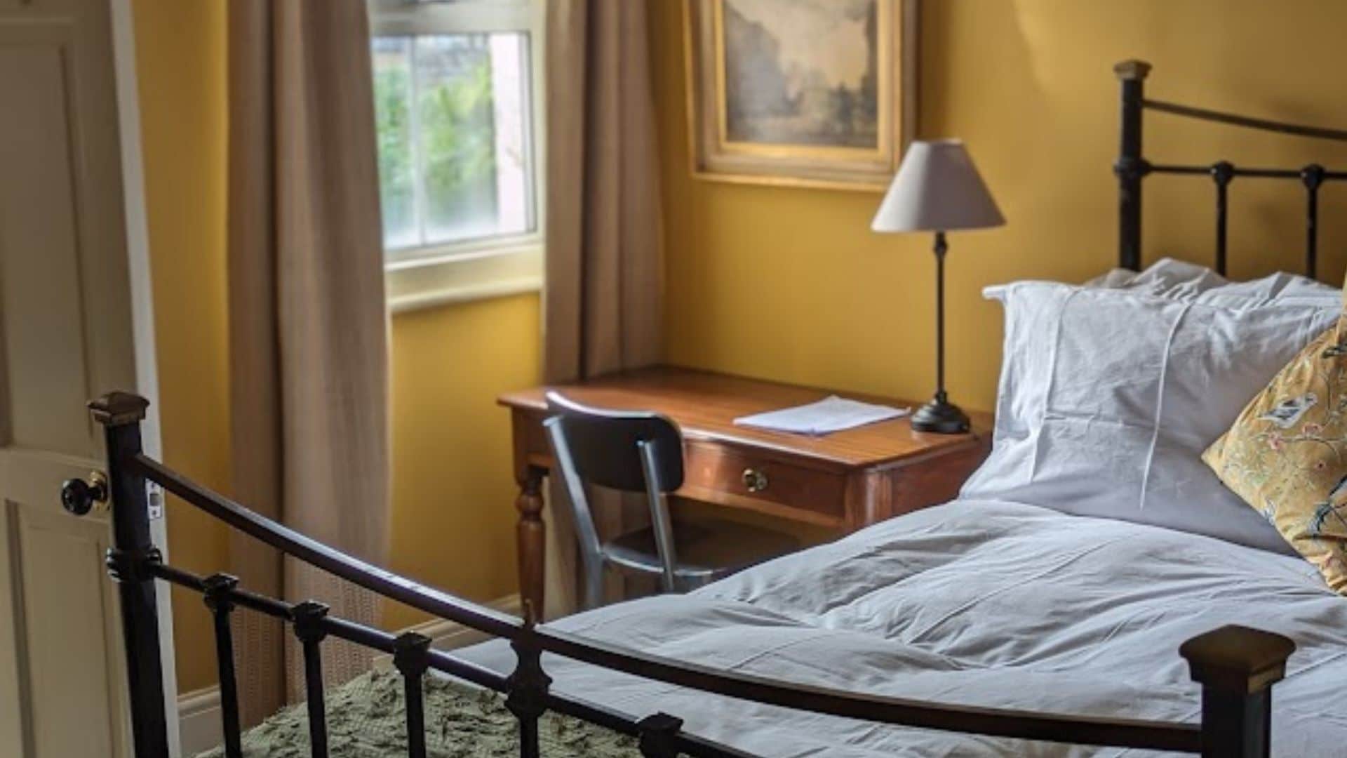 A bedroom with a bed, a desk, and a chair.