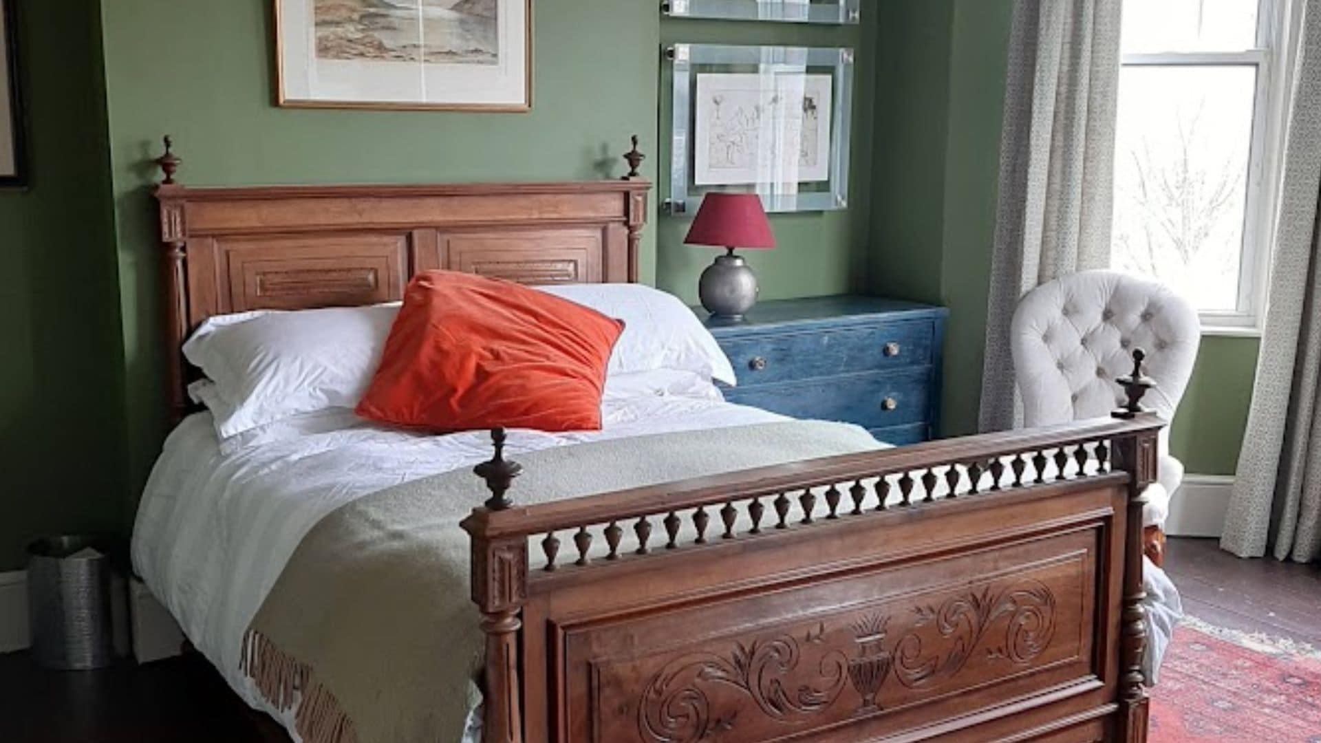 Ein Schlafzimmer mit einem hölzernen Bett, einem Nachttisch, einer Lampe und einem Sessel.