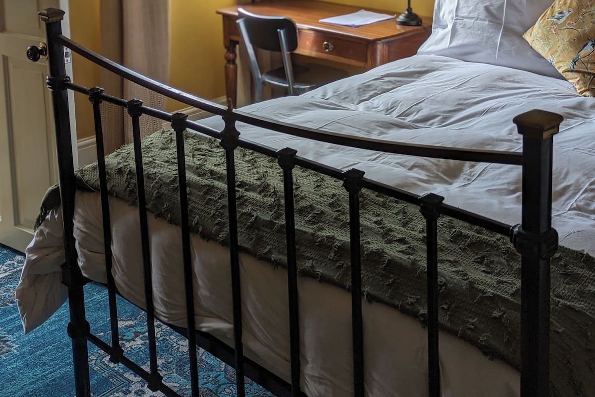 A bedroom with a bed, a desk, and a chair.