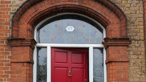 A red door with a number 17 above it, set within a brick archway. - 17 Trent Road  (London)