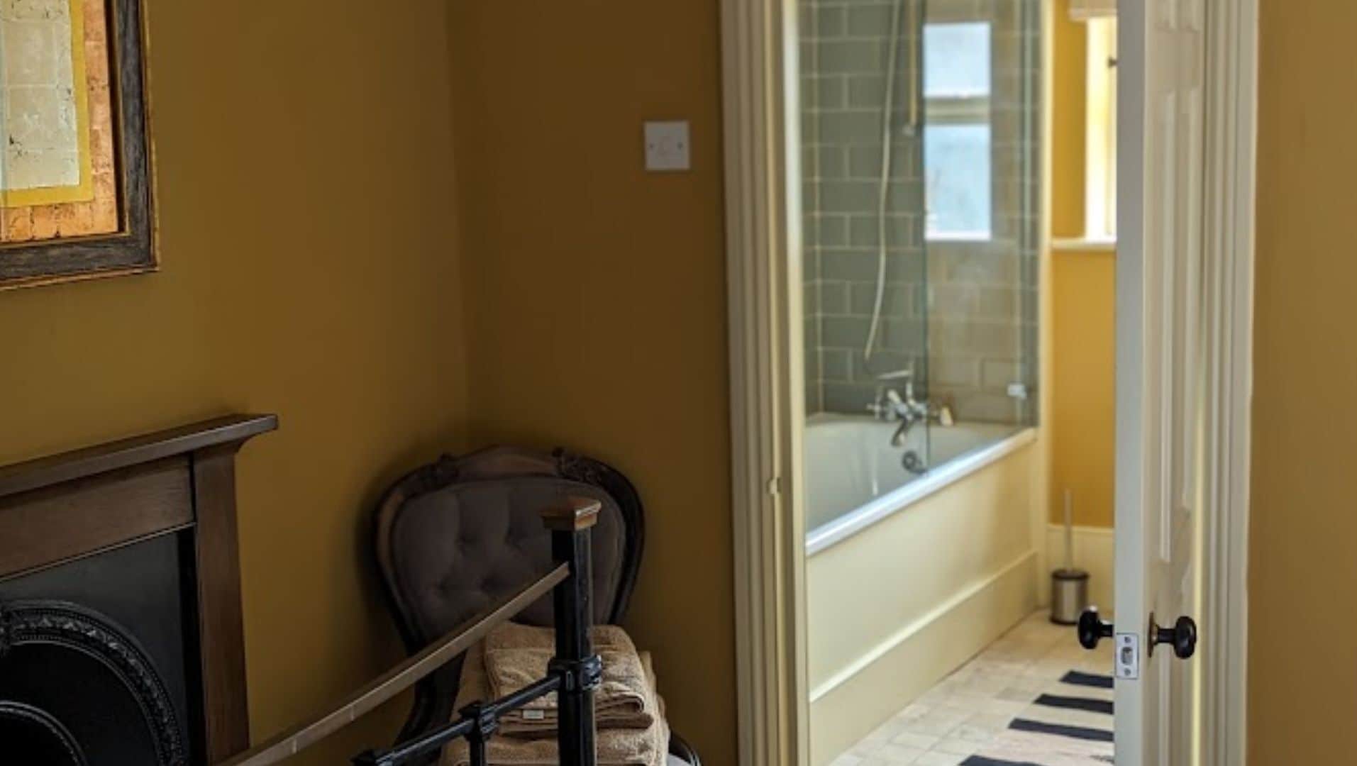 A bathroom with a bathtub, a towel rack, and a door leading to a shower area.