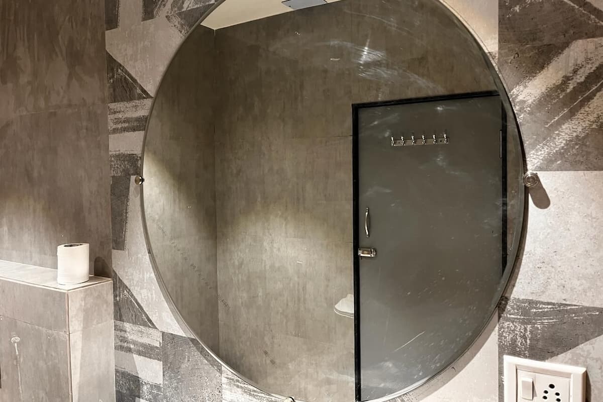 A circular, metallic room with a door and a light switch on the wall.