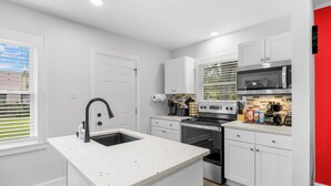 A modern kitchen with white cabinetry, a central island, a built-in oven, and a microwave. - zSALE! 2mi to Downtown & Front Street Attractions! (Wilmington)