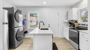 A modern kitchen with a built-in washer and dryer, a large island with a sink, and a stove. - zSALE! 2mi to Downtown & Front Street Attractions! (Wilmington)