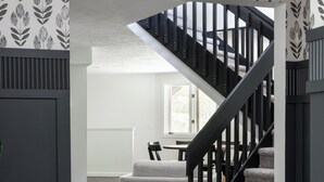 A modern interior with a staircase, a grey sofa, and a patterned wallpaper.