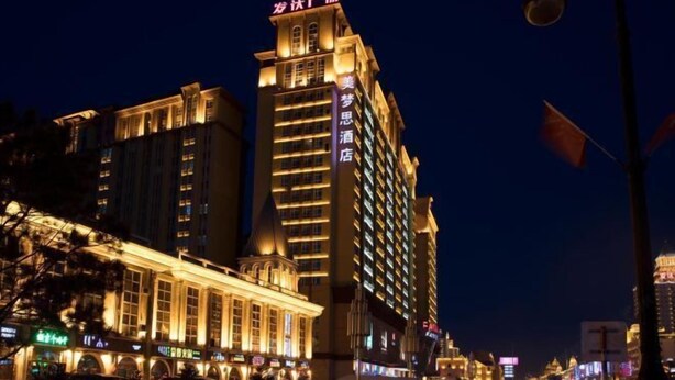 A multi-story hotel with illuminated signage and a prominent entrance. - Memo's Hotel (Manzhouli)