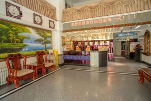 A hotel lobby with a reception desk, seating area, and a large painting on the wall. - Memo's Hotel (Manzhouli)