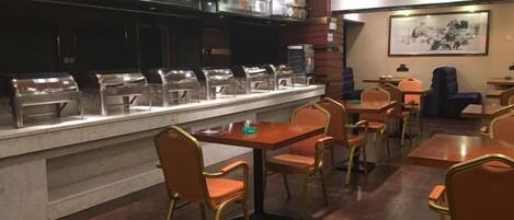 Un espace buffet comprenant plusieurs stations de service en libre-service, une grande variété de plats et des tables où s’asseoir.