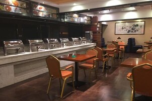 Zona tipo bufé con varias estaciones de autoservicio, una amplia variedad de alimentos y disposición de mesas.