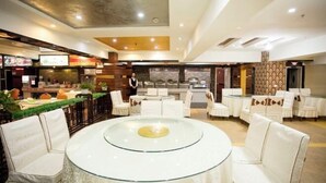 A hotel lobby with a central round table, white cushioned seating, a bar area, and a patterned wall. - Memo's Hotel (Manzhouli)