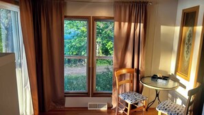 A room with a large window, a chair, a small table, and a framed picture on the wall. - Spacious cabin right on the lake, perfect for your next family vacation! (Luck)