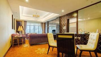 Quarto de hotel com sofá, cadeiras, mesa pequena e espelho decorativo.