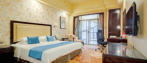 A hotel room with a large bed, a desk, a chair, a television, and a view of the outdoors.