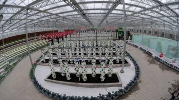 A greenhouse structure with a circular central area surrounded by rows of plants.
