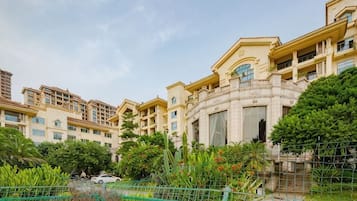 Un edificio residencial de varios pisos con balcones, un patio central y abundante vegetación.