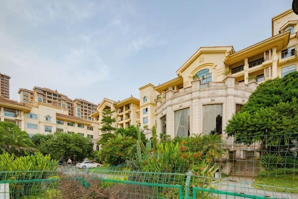 Un edificio residencial de varios pisos con balcones, un patio central y abundante vegetación.