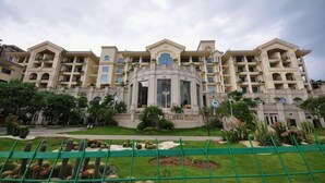 A multi-story hotel with a central courtyard, balconies, and a landscaped garden. - Green Bin Phoenix Hotel(Beiliu Country Garden ) (Beiliu)