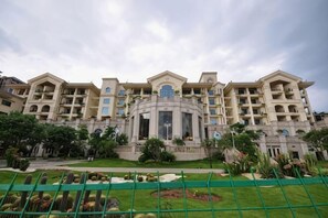 A multi-story hotel with a central courtyard, balconies, and a landscaped garden.