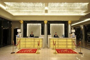 A hotel reception area with two reception desks, a chandelier, and a red carpet. - Green Bin Phoenix Hotel(Beiliu Country Garden ) (Beiliu)