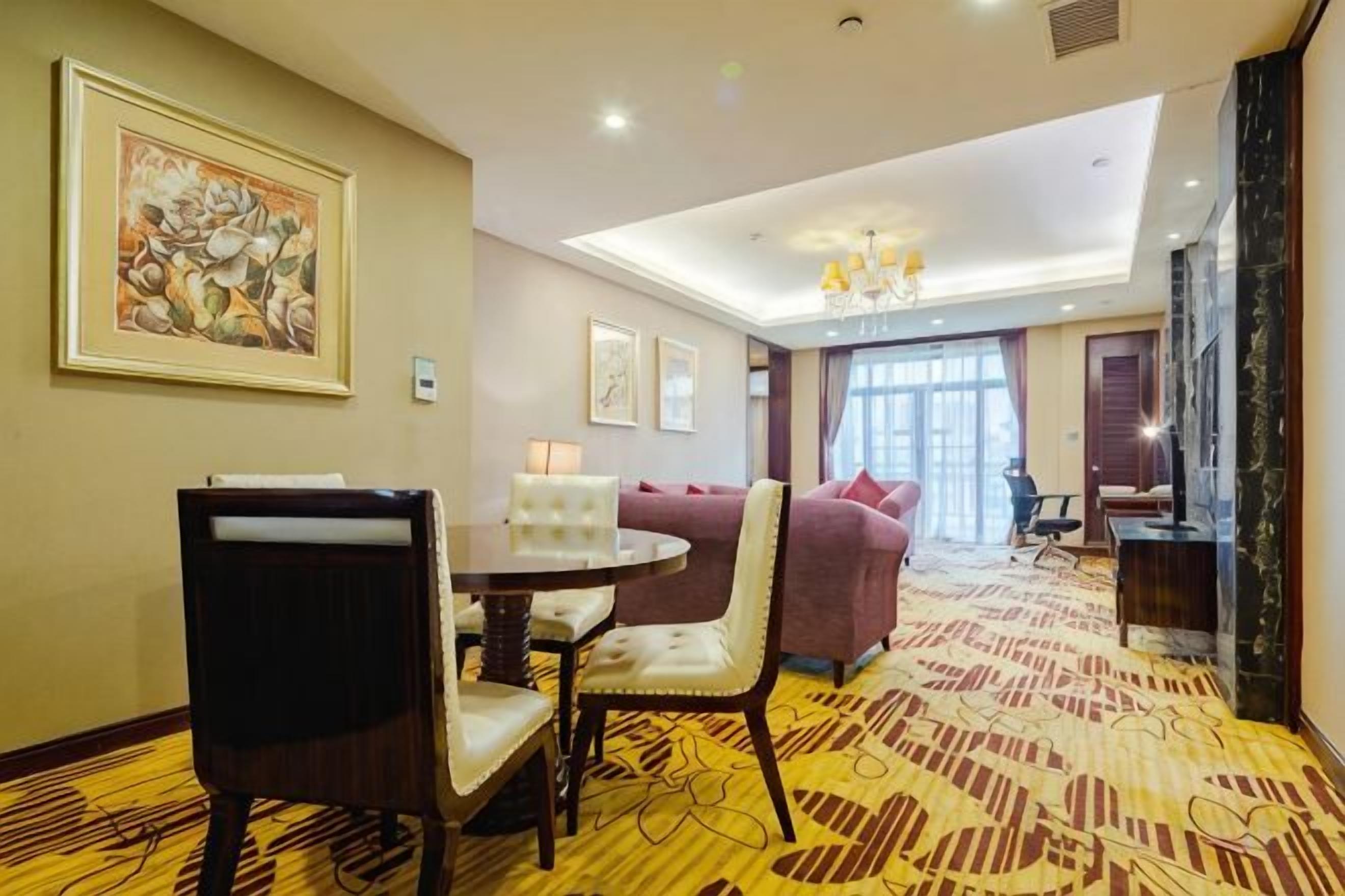 A hotel room with a dining area, a sofa, and a chandelier.