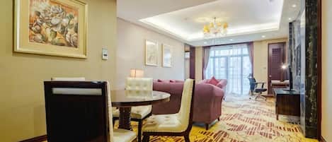 A hotel room with a dining area, a sofa, and a chandelier.