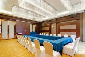 A conference room with a long table, white chairs, and a chandelier. - Green Bin Phoenix Hotel(Beiliu Country Garden ) (Beiliu)