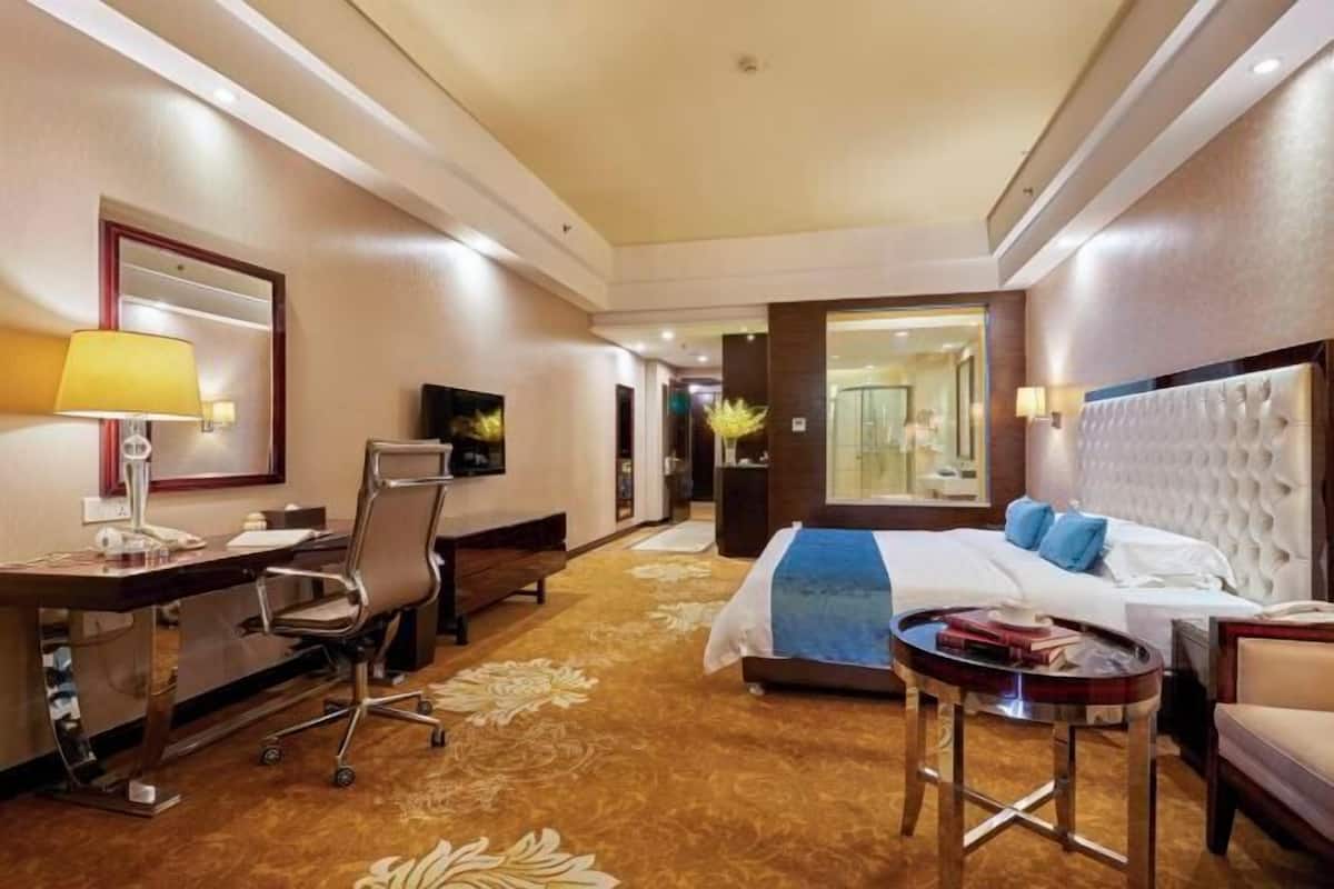 A hotel room with a bed, desk, chair, and a small table.