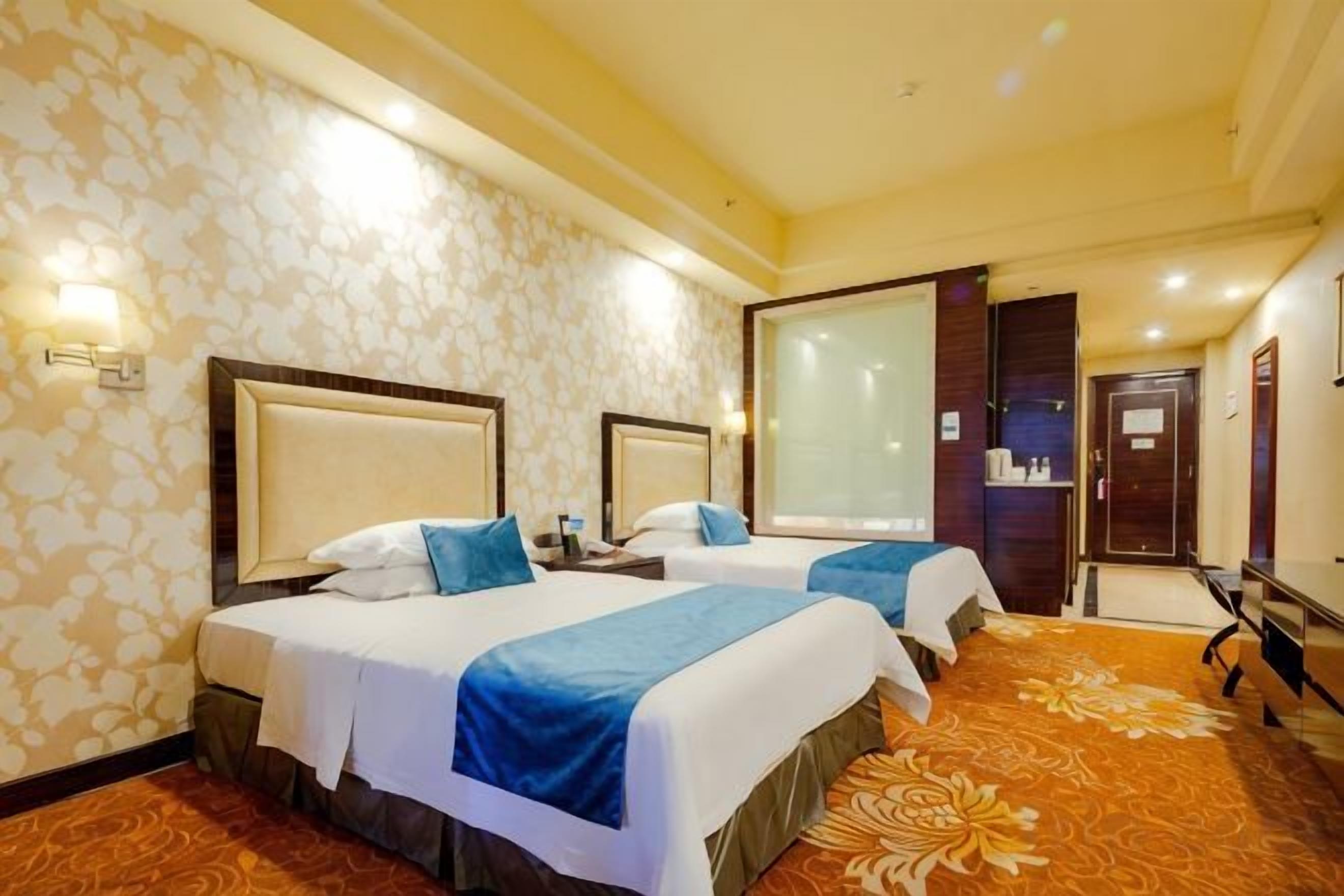 Una habitación de hotel con dos camas, un ventanal grande y piso alfombrado.