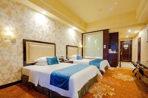 Una habitación de hotel con dos camas, un ventanal grande y piso alfombrado.