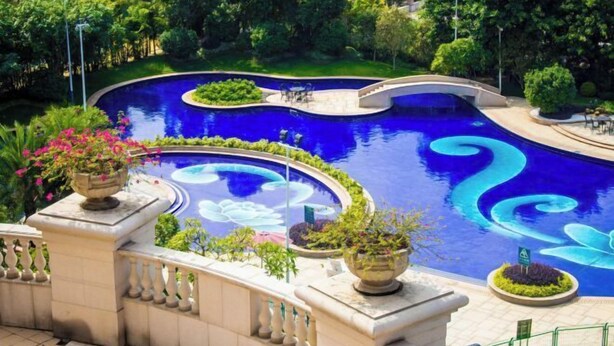 A landscaped pool with a winding design, surrounded by lush greenery and decorative planters. - Green Bin Phoenix Hotel(Beiliu Country Garden ) (Beiliu)
