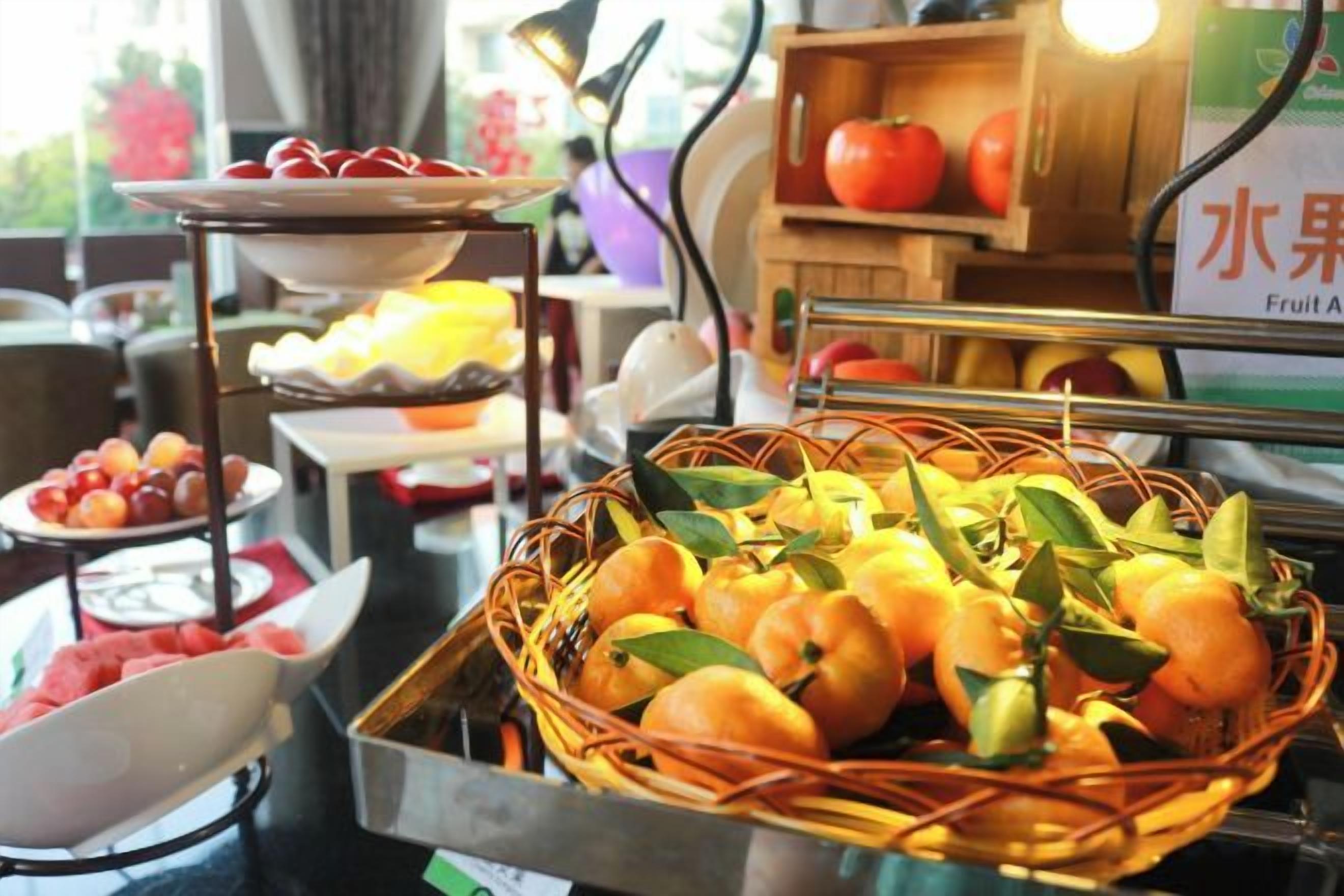 A buffet with various fruits and a fruit stand.