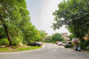 Una calle residencial con coches estacionados y abundante vegetación.