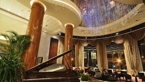A grand lobby with a grand piano, large columns, and a high ceiling with a decorative light fixture. - Green Bin Phoenix Hotel(Beiliu Country Garden ) (Beiliu)