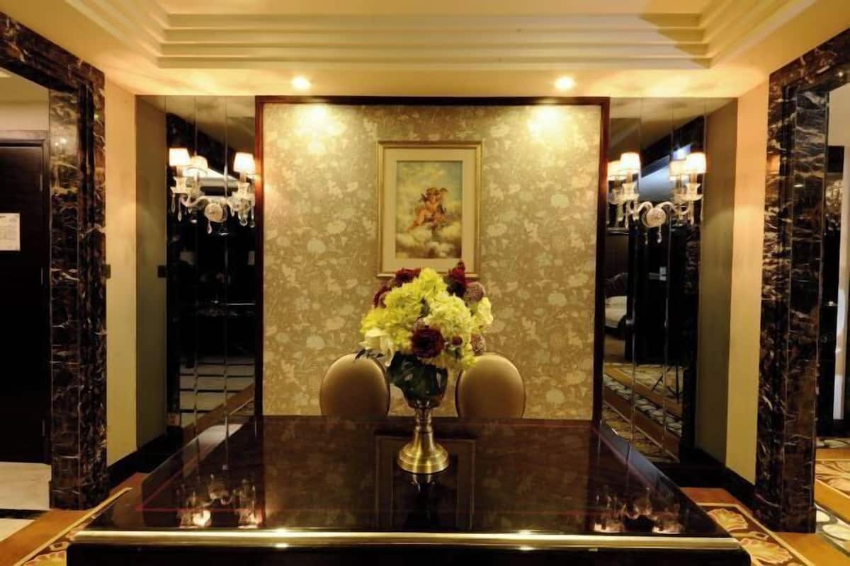 A hotel lobby with a marble reception desk, a framed artwork on the wall, and a vase of flowers.