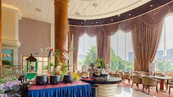 A hotel lobby with a central round table, seating area, and large windows.
