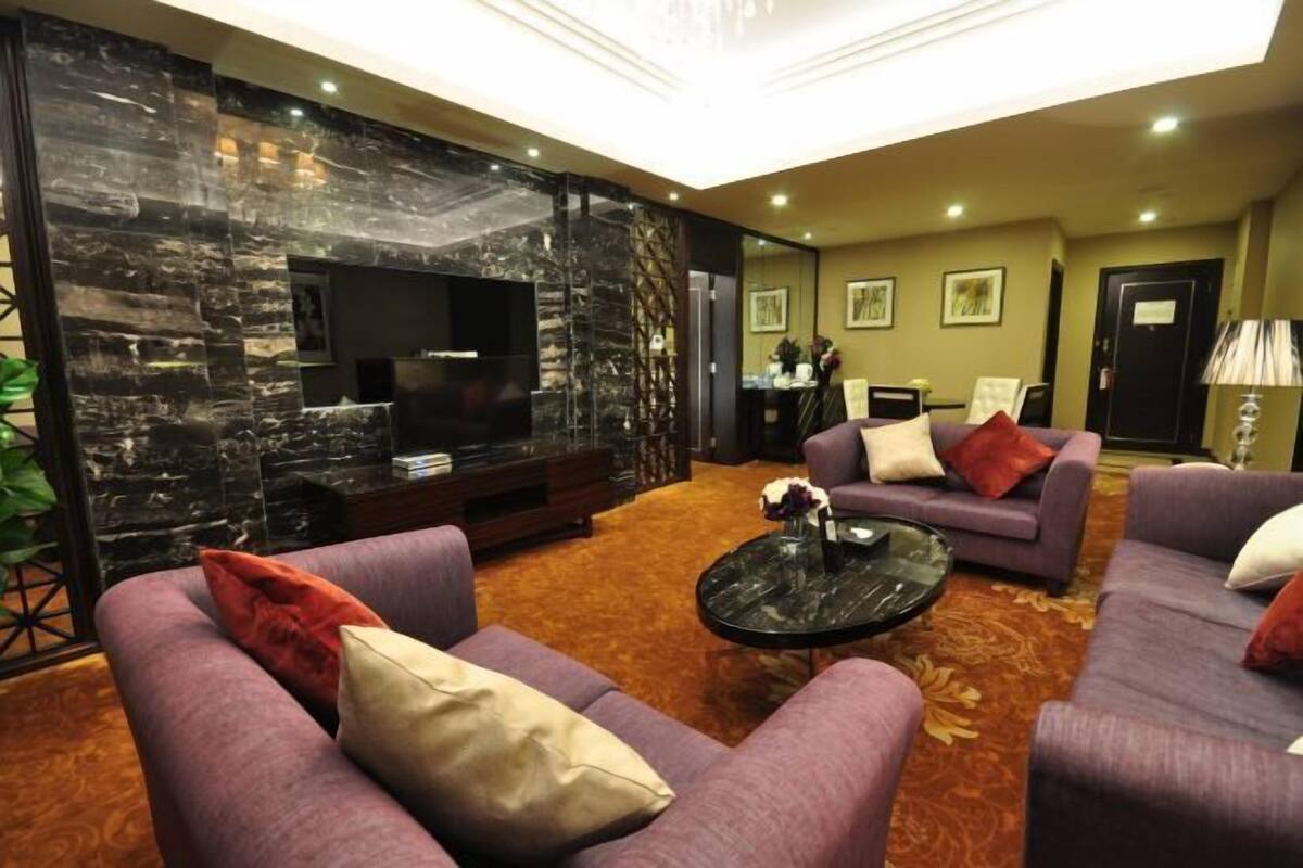 A modern living room with a stone accent wall, a flat-screen TV, two sofas with cushions, a coffee table, and a carpeted floor.