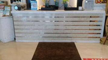 Un comptoir d’accueil au design moderne, un tapis marron et un code QR sur le mur.