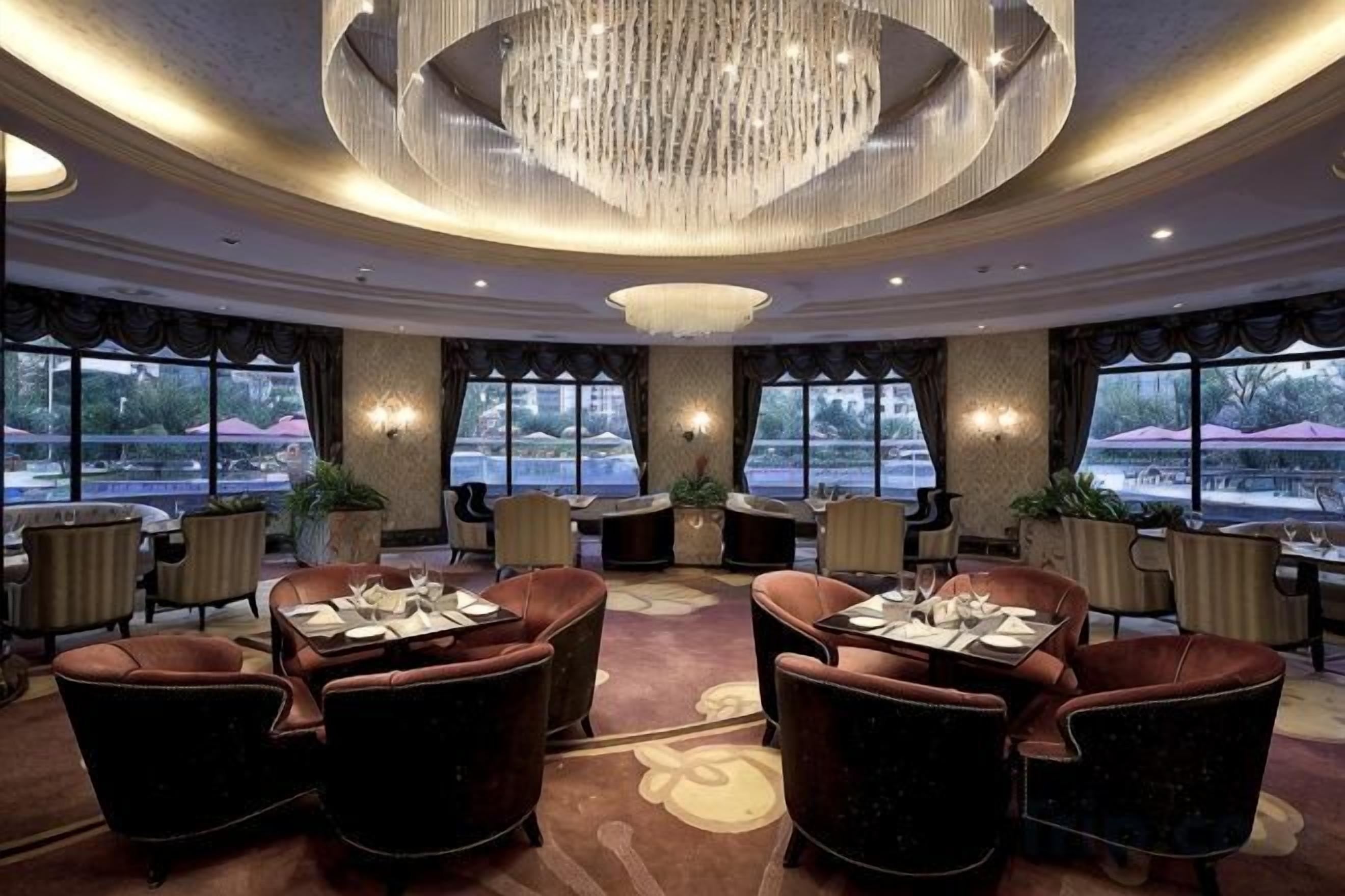 Un hall d’hôtel agrémenté d’un lustre, de fauteuils en cuir et de grandes fenêtres offrant une vue panoramique.