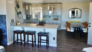 A modern kitchen with a large island, bar stools, and a dining area with chairs.