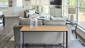 A spacious living room with a grey sofa, a wooden coffee table, and a ceiling fan.